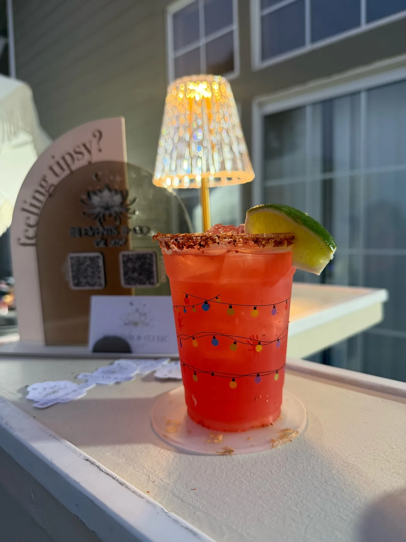 Red signature cocktail with lime and party stirrer